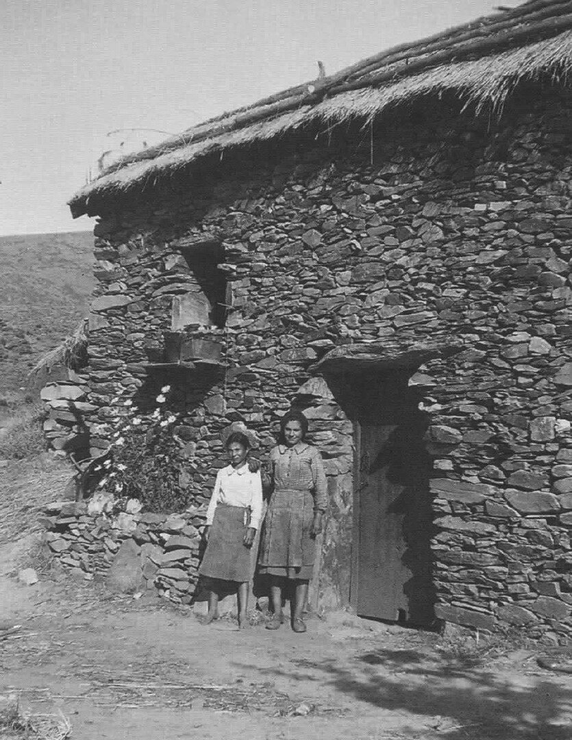 Vergrösserte Ansicht: Image caption: A house in Castanheira adorned with flower arrangements on its facade, with the women who inhabit standing in the foreground. Photograph: Maria Lamas, 1948. (Lamas, Maria, As Mulheres do Meu País, Caminho, 2002)